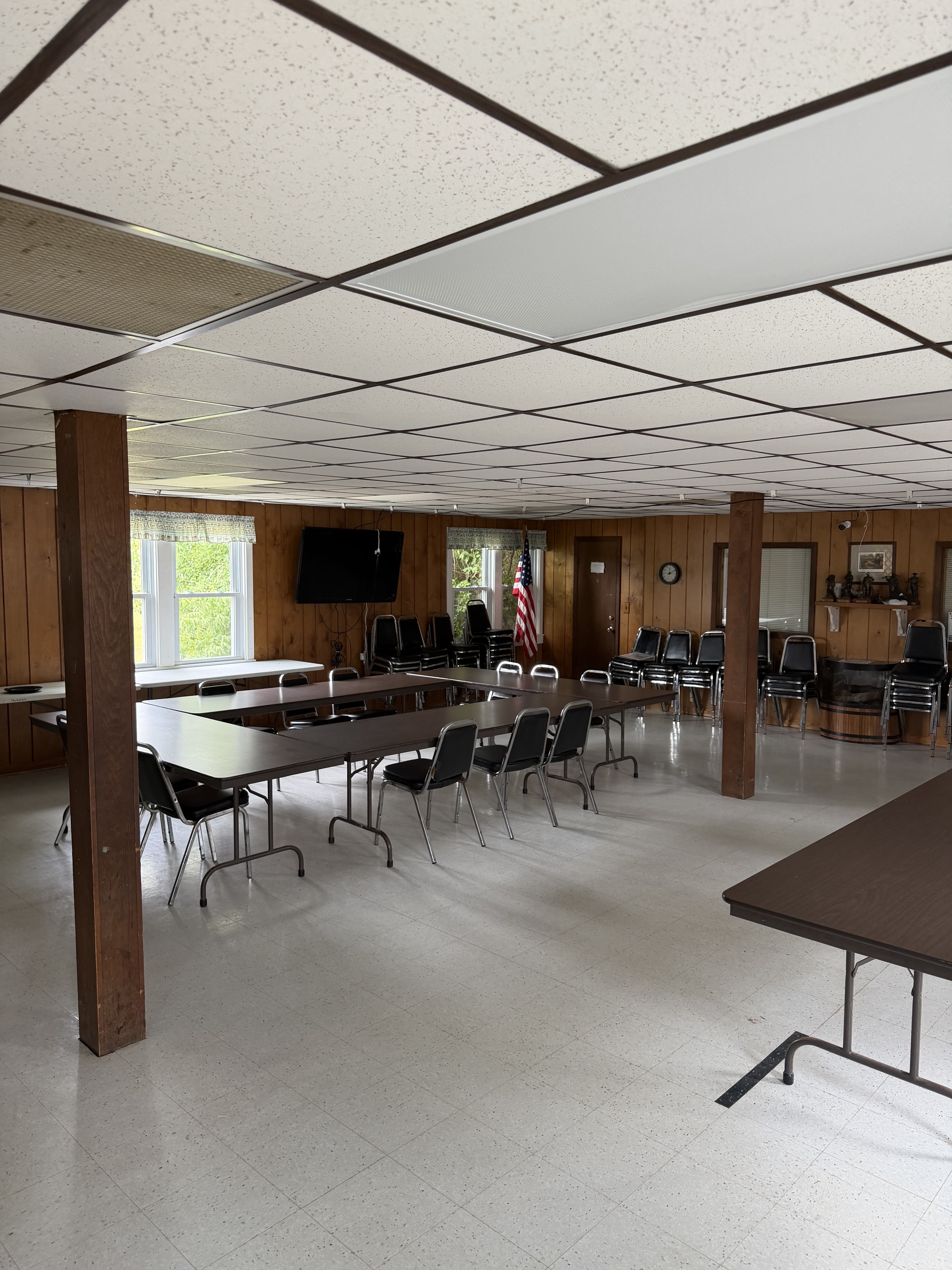 Deer Creek Recreation Club clubhouse meeting room with long tables, chairs, American flag, and flat screen TV