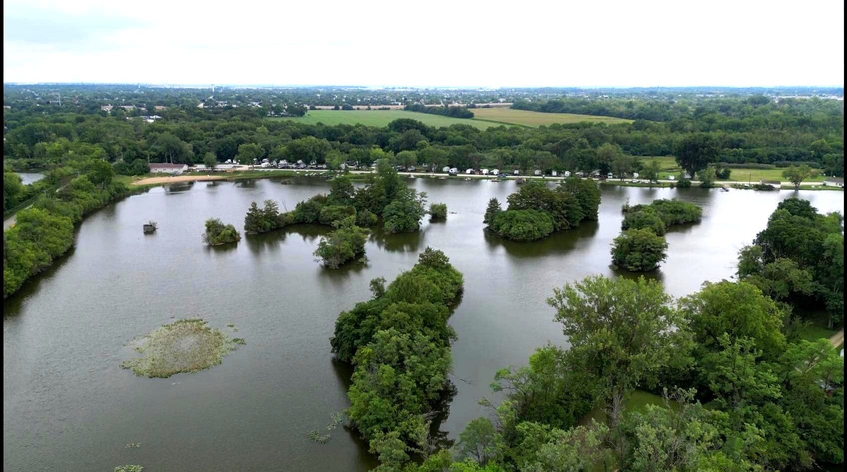 Aerial drone view of both Deer Creek lakes showing wooded islands campground and beach area in Plainfield Illinois