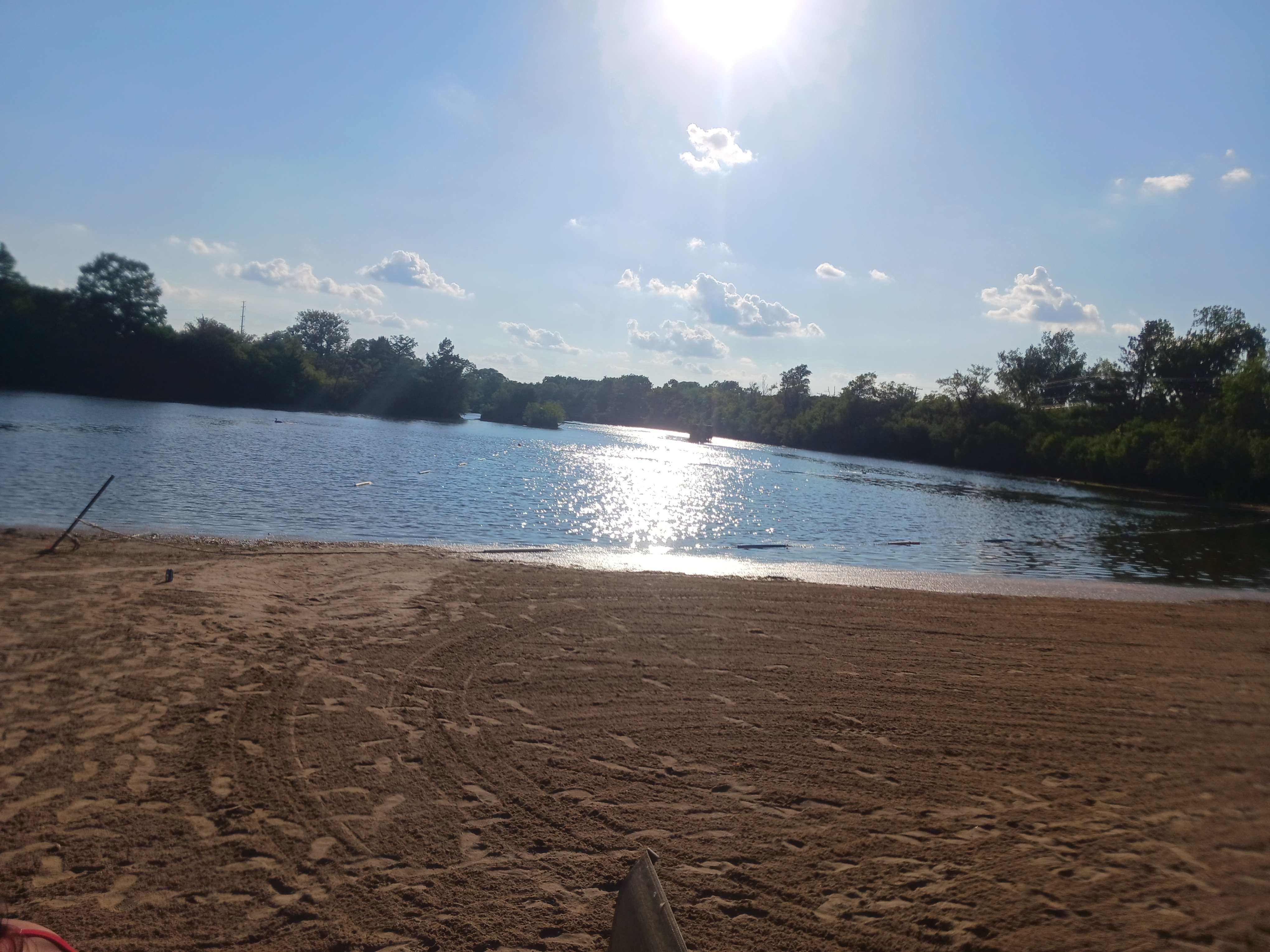 Wide view of the Deer Creek Recreation Club private sandy beach and lake on a sunny summer day