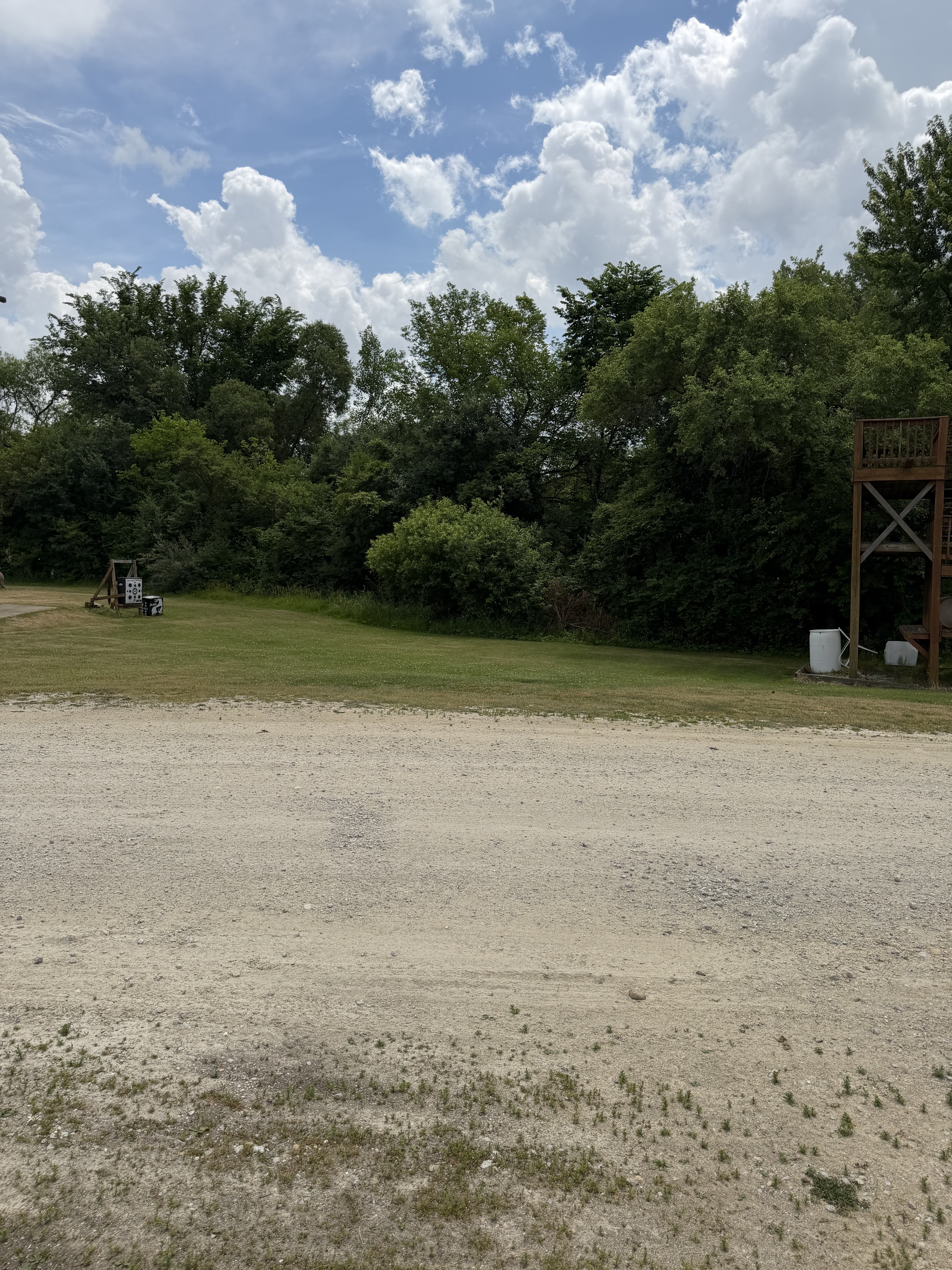 Wide view of the Deer Creek Recreation Club trap field with shooting pad, archery targets, and the Trap House tower visible at right